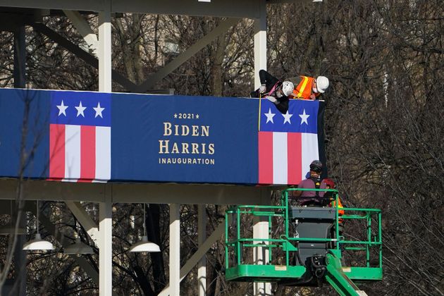 Workers adjust the bunting on a riser across from the White House on Thursday