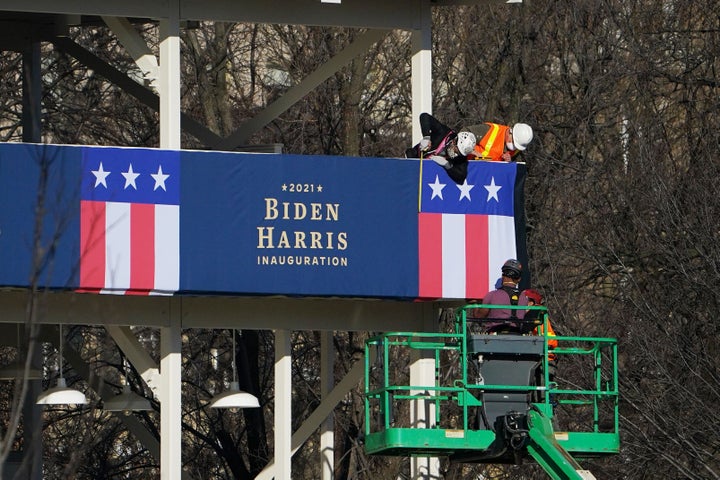 Workers adjust the bunting on a riser across from the White House on Thursday.