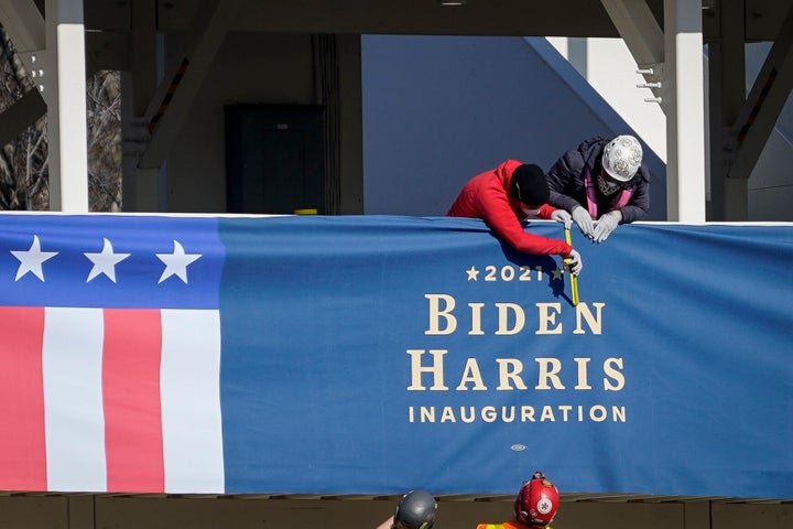 Workers erect "Biden-Harris" bunting on a press riser Thursday along what would have been the inaugural parade route near the