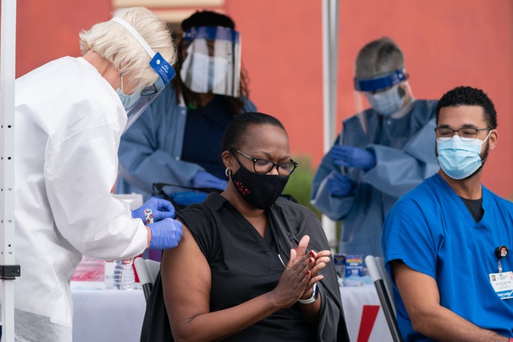 Chatham County Health Department nurse manager Tammi Brown, center, applauds after receiving a dose of the Pfizer-BioNTech COVID-19 vaccine from R.N. Nancy Toth outside of the Chatham County Health Department in Savannah, Georgia. 