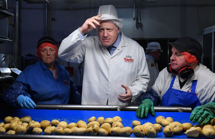 Boris Johnson helps quality control staff during a general election campaign visit to the Tayto Castle crisp factory in County Armagh, Northern Ireland, in 2019