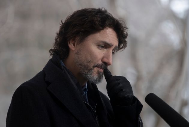 Prime Minister Justin Trudeau scratches his face as he listens to a question during a news conference...