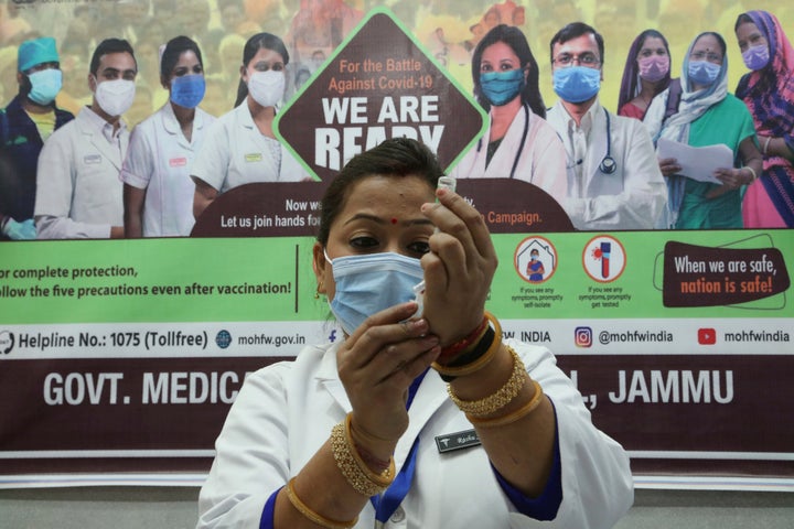 A health worker prepares to administer COVID-19 vaccine to a doctor at a government Hospital in Jammu, India, Saturday, Jan.1