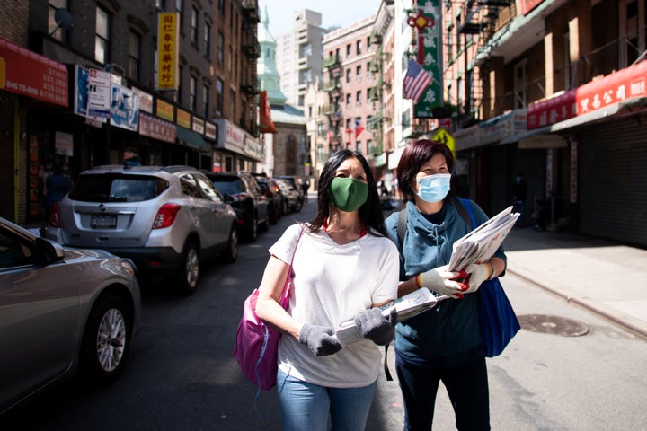 Shirley Ng (l) , a volunteer with the Chinatown Block Watch neighborhood patrol group, distributes Chinese newspaper along a 