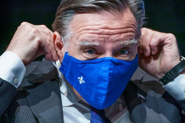Quebec Premier Francois Legault slips on his mask following a news conference in Montreal on Jan. 19,...