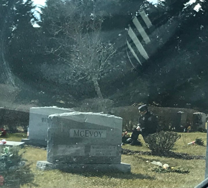 A lone man in a blue uniform kneels at the grave of Beau Biden at St. Joseph on the Brandywine church in Greenville, Delaware