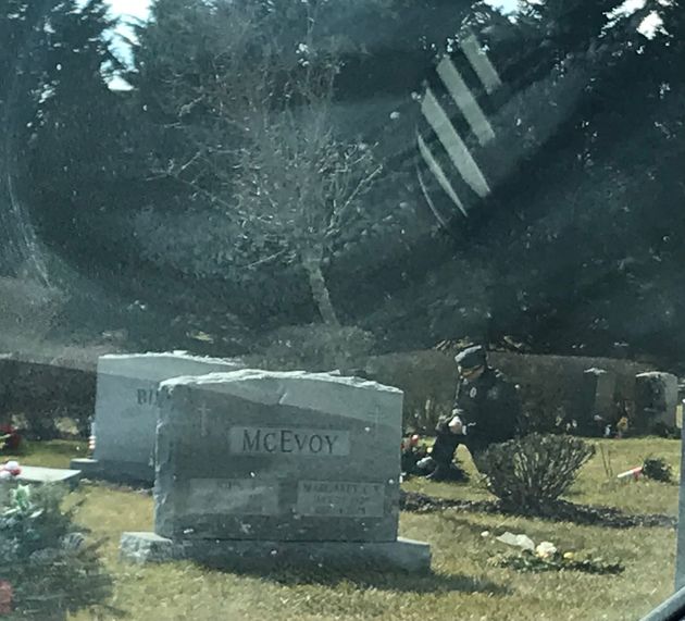 A lone man in a blue uniform kneels at the grave of Beau Biden at St. Joseph on the Brandywine church in Greenville, Delaware, on Wednesday.