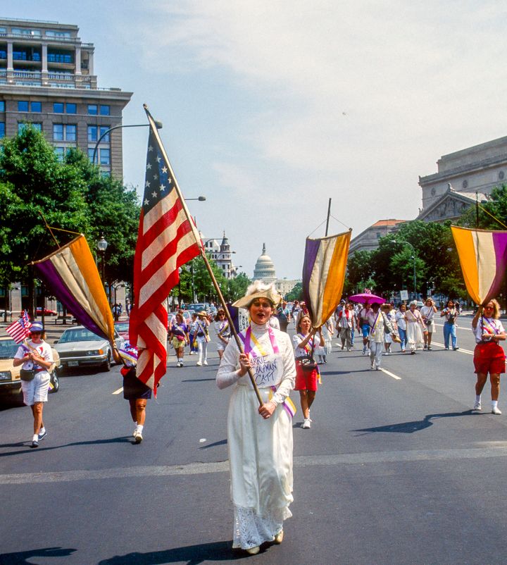 憲法修正第19条の成立75周年を祝ってワシントンで行われたパレード。紫、白、金色のフラッグ（旗）を持つ女性たちが行進した。
