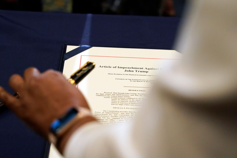 Staff member Latrice Powell placed the article of impeachment against Trump on a table for Pelosi to sign.