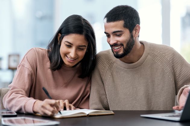 Shot of a young couple going over notes together while working from home