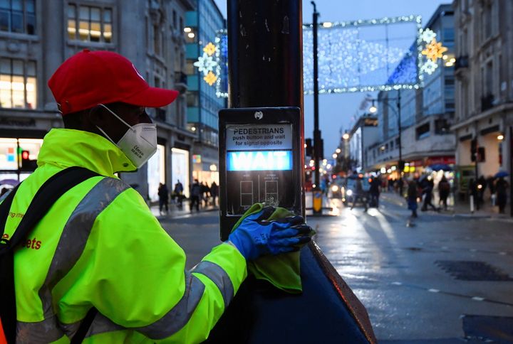 A street cleaner pictured in December sanitising the button on a pedestrian crossing
