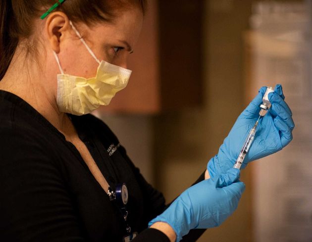 A pharmacist prepares vials of coronavirus vaccine (file picture) 