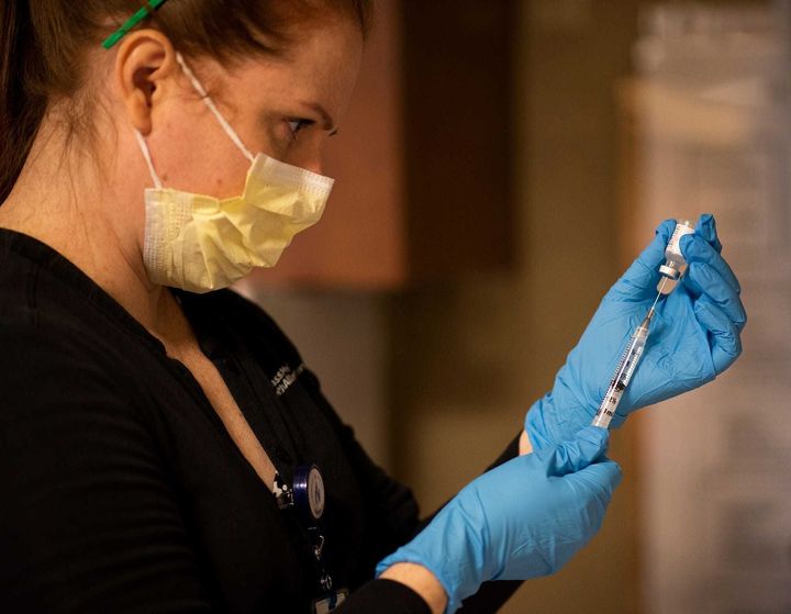 A pharmacist prepares vials of coronavirus vaccine (file picture) 
