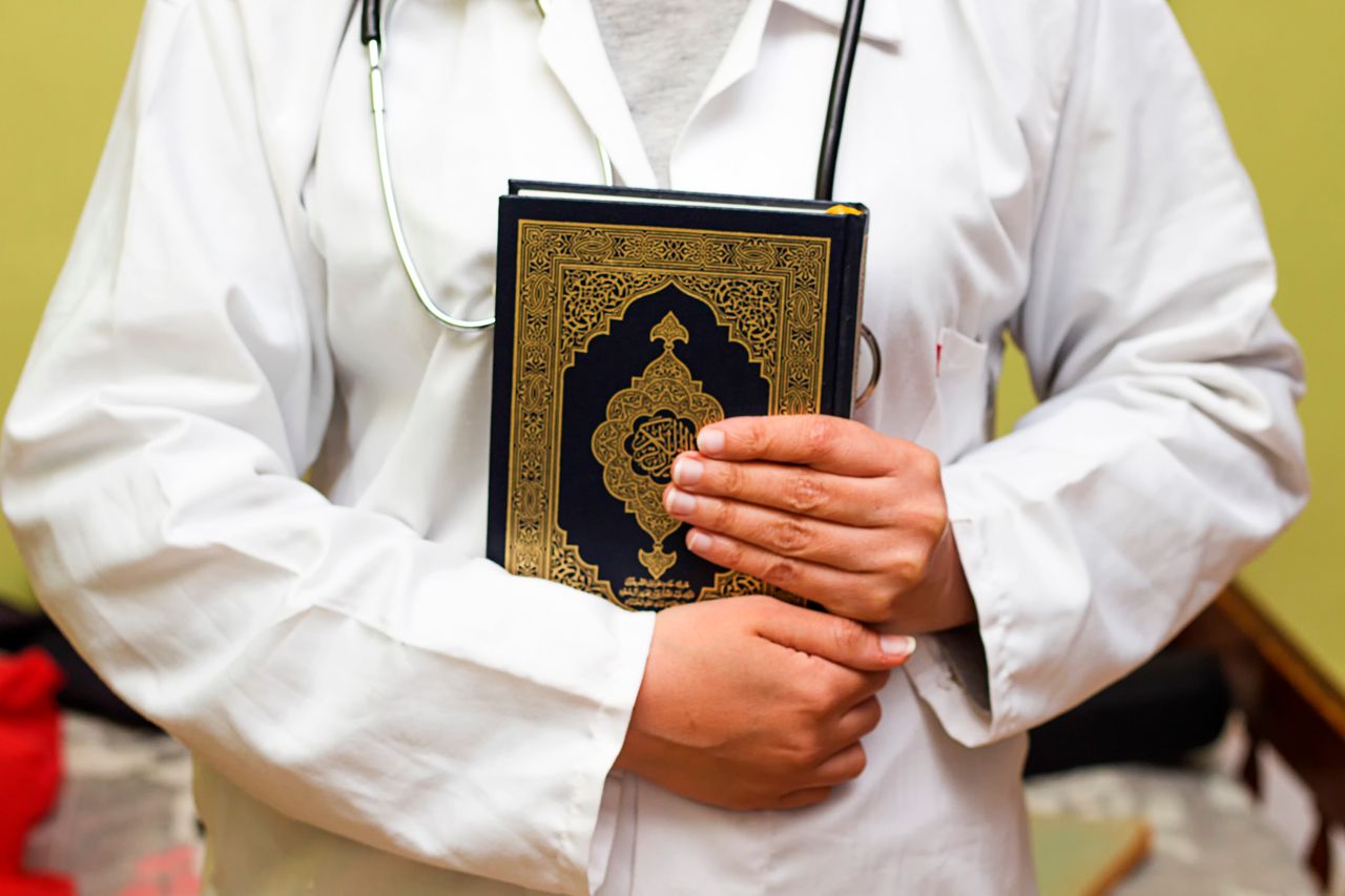 Doctor with stethoscope holding Holy Quran