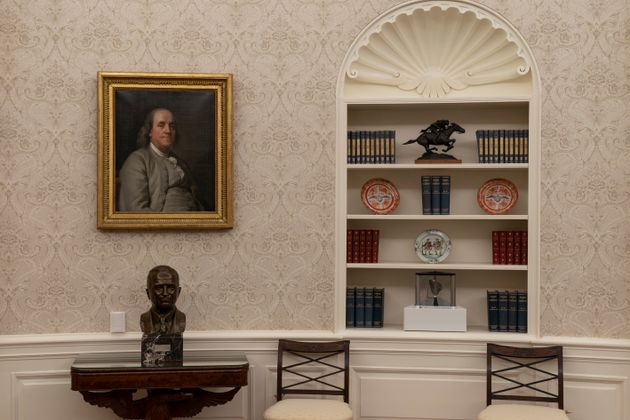 A portrait of Benjamin Franklin hangs above a bust of former President Harry Truman in President Joe Biden's Oval Office. A moon rock is displayed on the bottom shelf of a nearby bookcase.