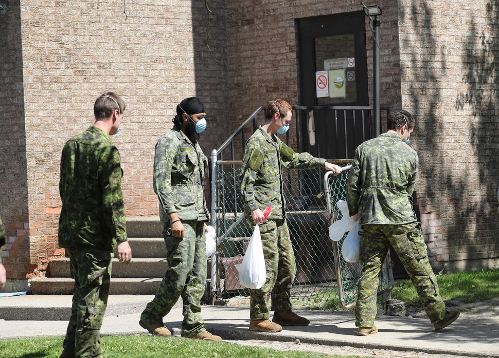 Military personnel are seen changing shifts behind the Eatonville Care Centre in Toronto on May 26, 2020.
