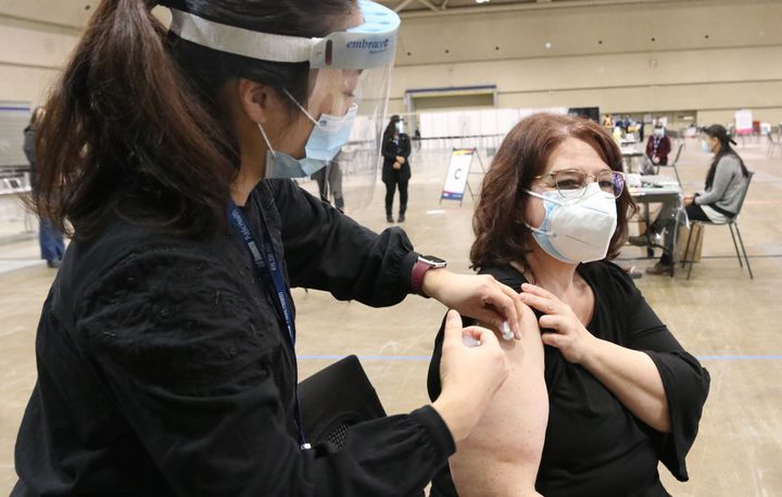 A woman receives a vaccine for COVID-19 at the Metro Toronto Convention Centre in Toronto on Jan. 18, 2021.