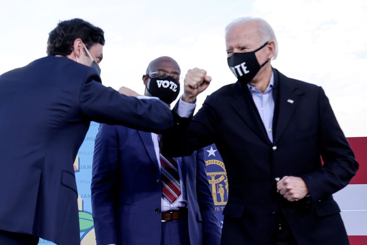 President Joe Biden, right, and Sens. Jon Ossof, left, and Rev. Raphael Warnock, newly elected in Georgia, promised voters $2,000 checks. What that promise meant is the subject of debate.
