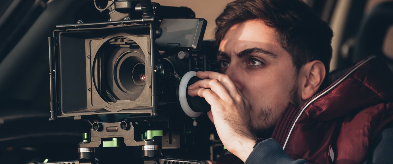 Behind the scene. Cameraman shooting the film scene with his camera on outdoor location