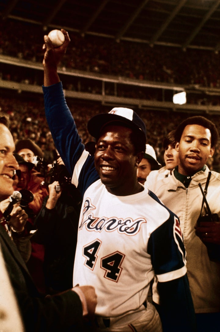 Hank Aaron holds up the ball here that broke Babe Ruth's home run record after he connected for his 715th career homer. With Aaron is his personal bodyguard, Calvin Wardlow.