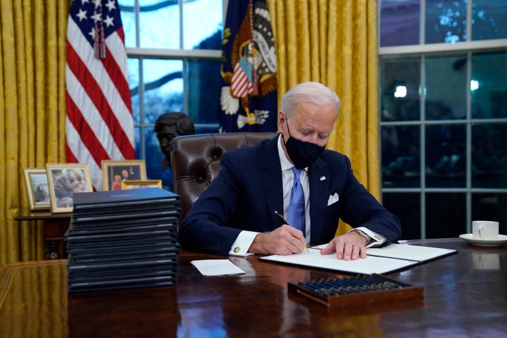 President Joe Biden signs his first executive order in the Oval Office of the White House on Wednesday, Jan. 20, 2021, in Was