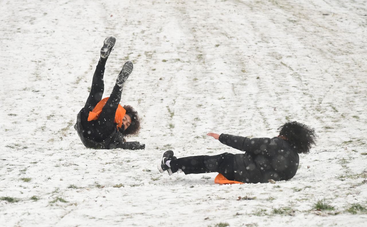 People sledging in a snowy Greenwich Park in London
