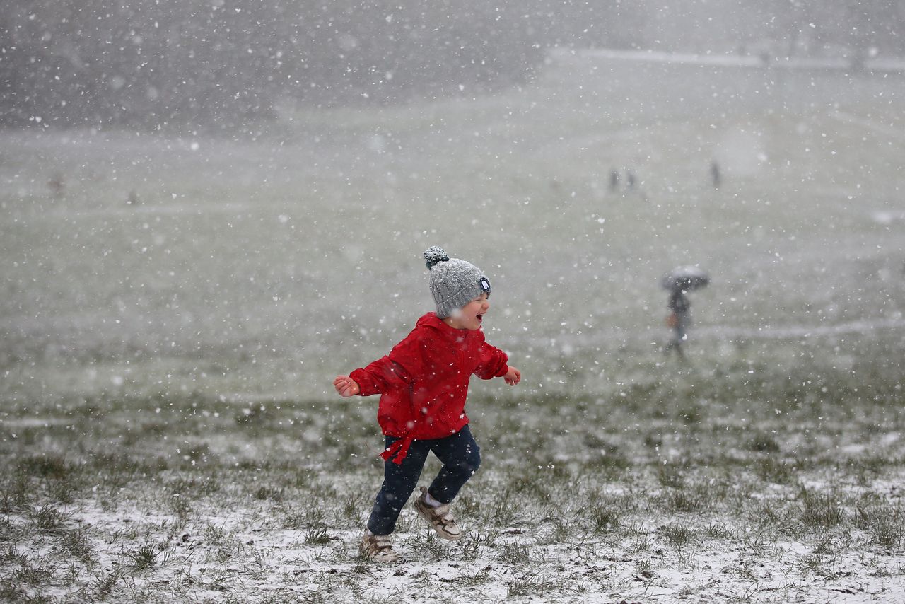 A child runs around as snow falls on Hampstead Heath in London.