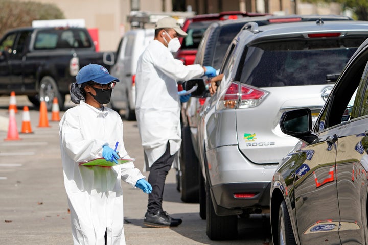 Healthcare workers process people waiting in line at a United Memorial Medical Center COVID-19 testing site Thursday, Nov. 19, 2020, in Houston. (AP Photo/David J. Phillip)