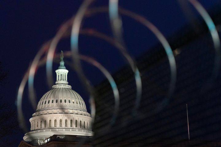 Le Capitole est visible à travers les barbelés au-dessus des clôtures, le 16 janvier 2021, à Washington alors que la sécurité est renforcée avant l’investiture du président élu Joe Biden et du vice-président élu Kamala Harris.