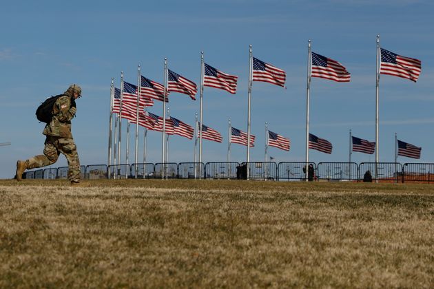 A National Guardsman walks past flags on the National Mall, four days after the inauguration of President Joe Biden, Sunday, Jan. 24, 2021 in Washington.(AP Photo/Rebecca Blackwell)