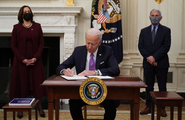 President Joe Biden signs executive orders on Jan. 21 as part of the COVID-19 response as Vice President Kamala Harris (left) and infections disease expert Dr. Anthony Fauci look on.