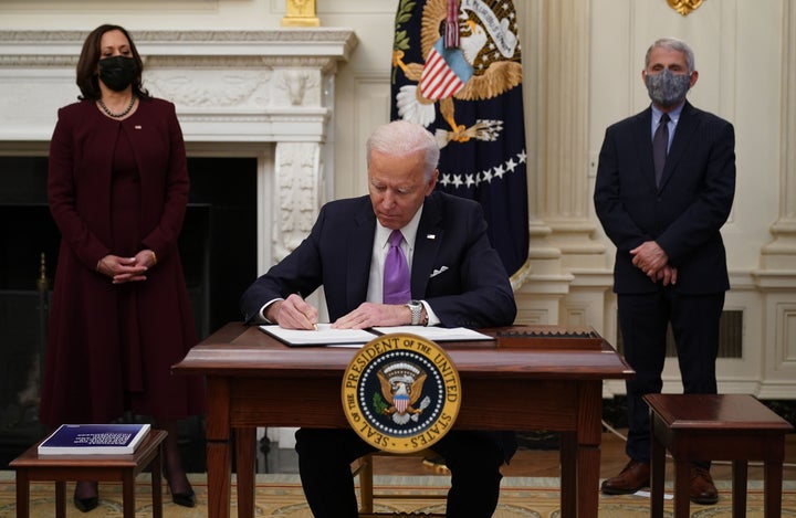 President Joe Biden signs executive orders on January 21 as part of the Covid-19 response as Vice President Kamala Harris (left) and infections disease expert Dr Anthony Fauci look on.