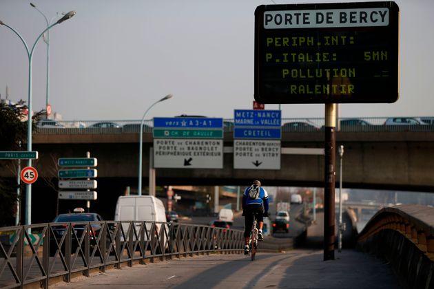 Un cycliste passe devant un panneau routier sur lequel est inscrit 