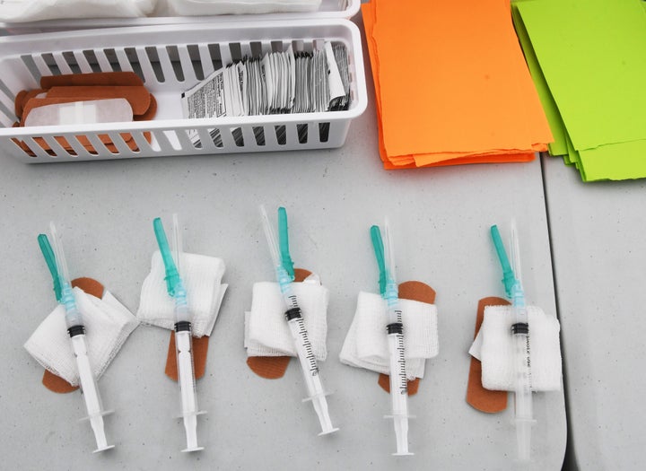 Syringes prepared by healthcare workers containing Moderna COVID-19 vaccine sit on a table at a vaccination drive-thru site i