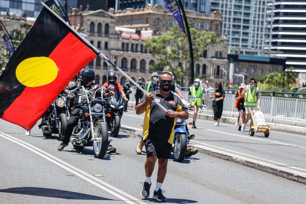 A protester waves the Aboriginal Flag across Victoria Bridge during the march. Crowds of people gathered in Brisbane, Queensland to protest against the Australia public holiday, which is a date synonymous with the beginning of many decades of persecution of Indigenous Australian people by the British colonialists.