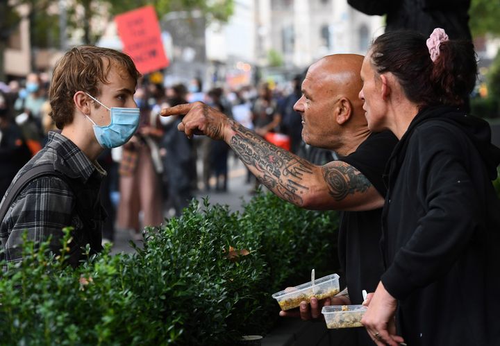 A couple (R) confront a protester as thousands of people attend an Australia Day protest in Melbourne in January 26, 2021. 