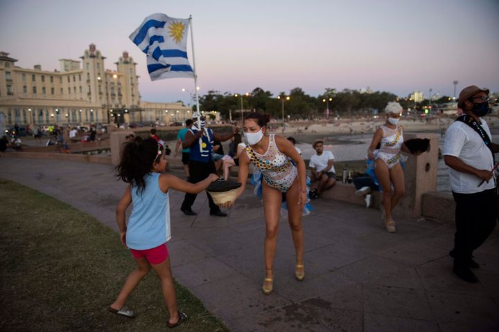 A girl hands over a coin to a Candombe artist performing at the Rambla of Montevideo, Uruguay, on Jan. 23, 2021. Countries with the least corruption have been best positioned to weather the health and economic challenges of the coronavirus pandemic, according to a closely-watched annual study released Thursday by anti-graft watchdog organization, Transparency International. Uruguay scored 71, putting it at 21st place on the list. 