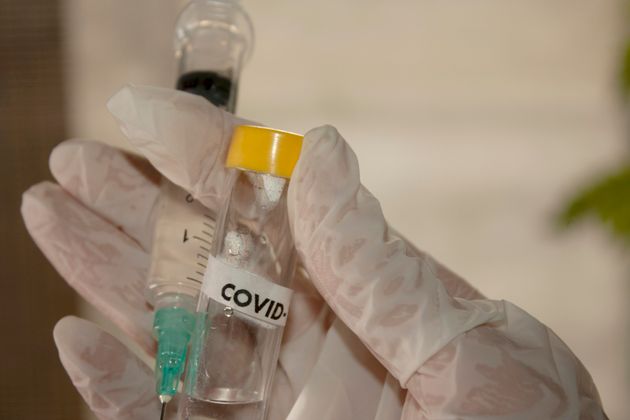 Hand holding syringe and possible covid-19 vaccine in