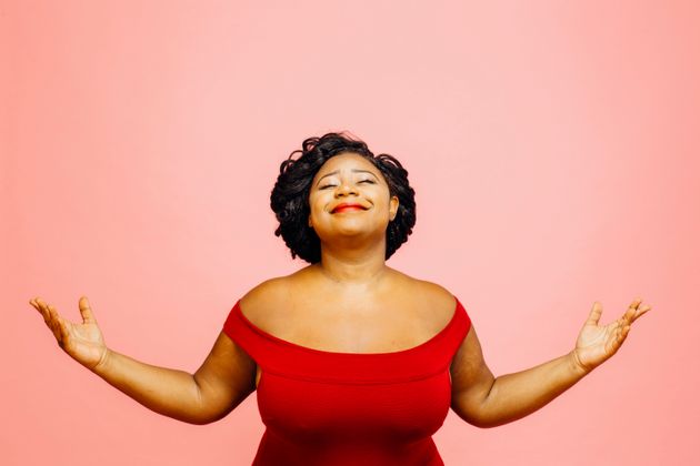 Portrait of a confident, satisfied and happy woman with both hands out, isolated on pink