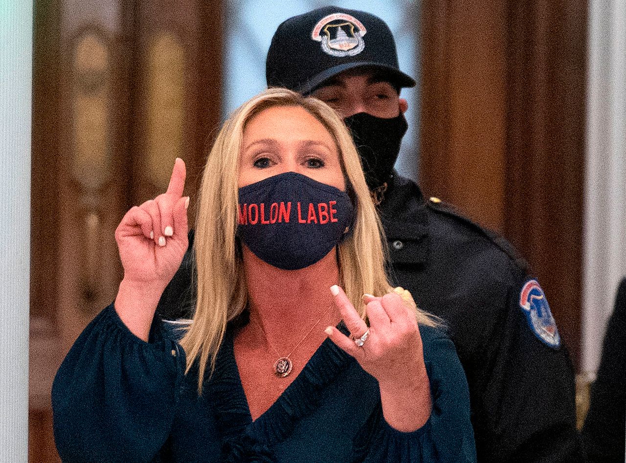 Greene shouts at journalists as she goes through security inside the U.S. Capitol on her way to the House of Representatives. She wore a face mask emblazoned the words "Molon Labe," an ancient Greek phrase meaning "Come and take them," a common refrain among gun rights extremists.
