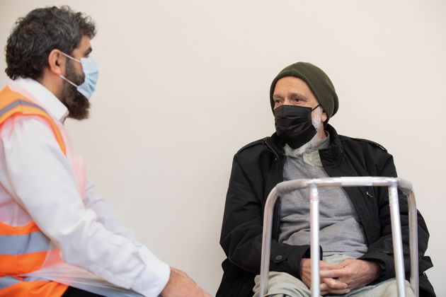 Pharmacist Aftab Rehman talks to his father Rehmat Khan after vaccinating him at the Ikhlas Islamic Education Centre in Derby