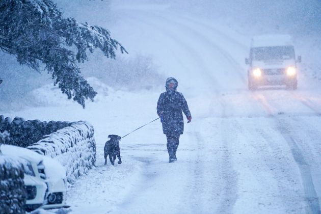 A dog walker and a van make their way along a snow covered road in Northumberland, as parts of the UK could be blanketed with up to seven inches (20cm) of snow in the next couple of days.