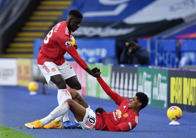 Axel Tuanzebe of Manchester United helps up teammate Marcus Rashford during a match on Dec. 26.