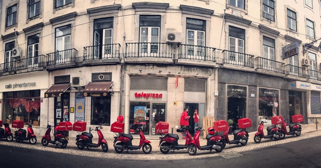 Lisbon, Portugal - May 04, 2017: Telepizza delivery mopeds parked outside the cafe. Vendors visible