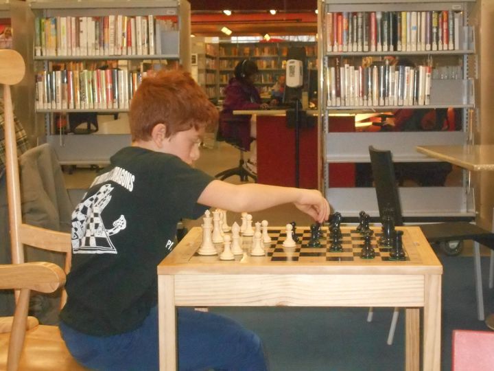Ivry at age 9, sets up a chessboard at the local library in preparation for his chess tutor.