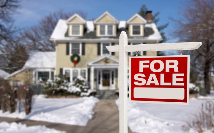 Home For Sale Real Estate Sign in Front of Beautiful New House in the Snow.