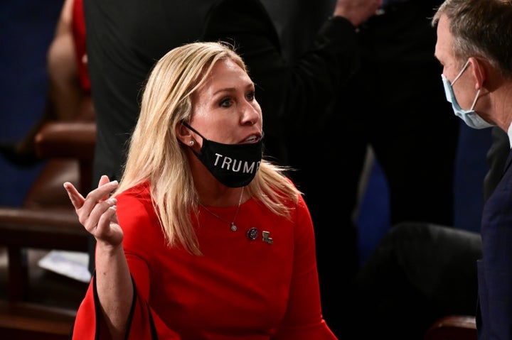 Rep. Marjorie Taylor Greene (R-Ga.), wearing a mask that reads "Trump won," speaks with a colleague on Jan. 3. The congresswoman has professed her support for many conspiracy theories, including that the 2020 election was stolen from Donald Trump.