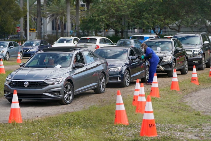 A health care worker gets information from people at a drive-thru COVID-19 vaccination site at Marlins Park, on Jan. 21, 2021