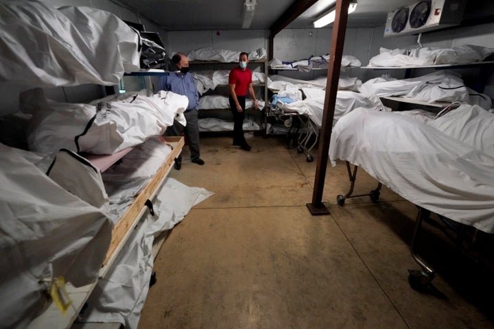 Mortuary owner Brian Simmons and mortician Triston McAuliff talk in a cooler holding deceased people Thursday, Jan. 28, 2021, in Springfield, Mo. (AP Photo/Charlie Riedel)