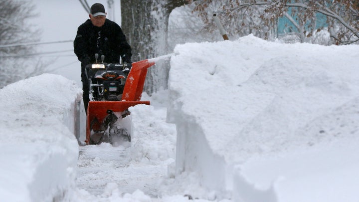 A man works to clear a sidewalk after a snowstorm Tuesday in Marlborough, Massachusetts.